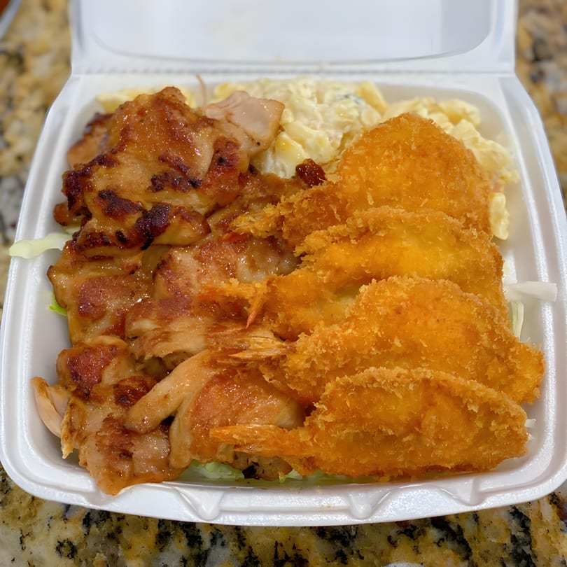 Hawaiian BBQ plate with grilled chicken, crispy fried shrimp, and macaroni salad in a takeout container.