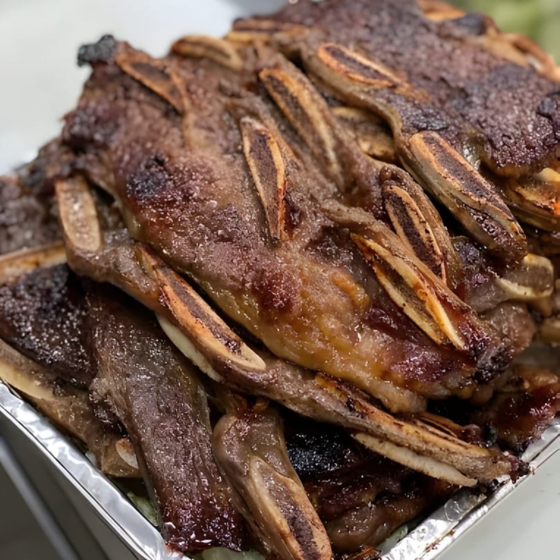 Close-up of grilled Hawaiian BBQ short ribs with visible bones and glistening marinade.