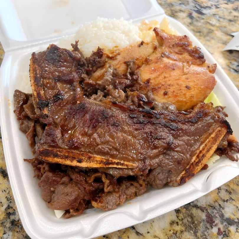 Young Hawaiian BBQ plate lunch with kalbi short ribs, BBQ chicken, rice, and macaroni salad.